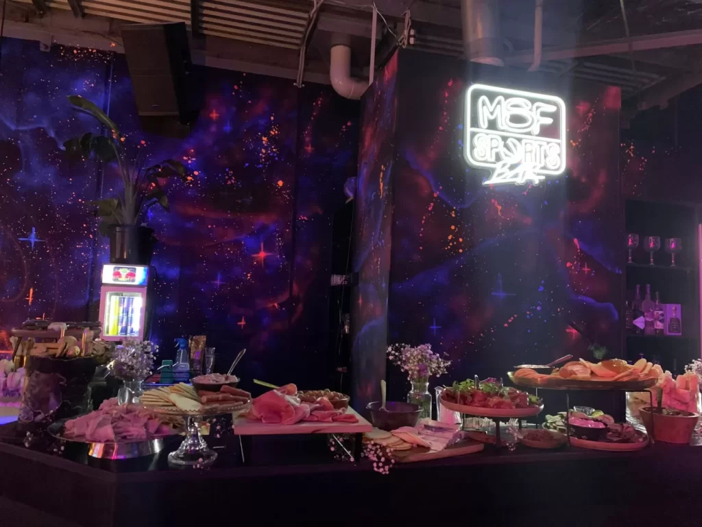 Cosmic-themed sports bar with snacks and neon sign.